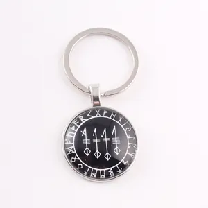 Close-up of a circular Viking keychain with Norse runes and symbols on a black base.