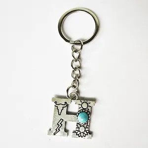 Close-up of retro silver initial H keychain with turquoise and western engravings