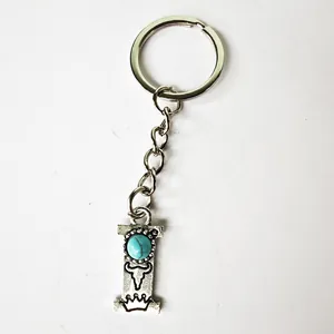 Close-up of vintage silver stainless steel letter I keychain with turquoise stone detail.