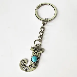 Close-up of vintage silver letter J keychain with turquoise and engraved patterns