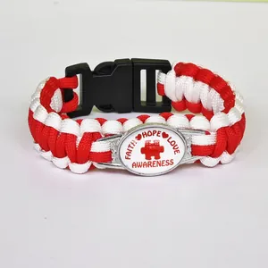 Close-up detail of red and white paracord bracelet with puzzle piece awareness charm
