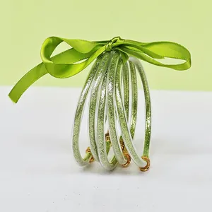 Close-up detail of 5-layer green glitter silicone bangle bracelets with silk ribbon bow
