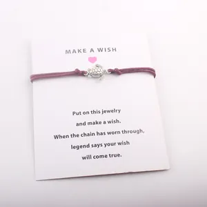 Vue détaillée d'un bracelet de vœux avec breloque tortue monté sur une carte cadeau