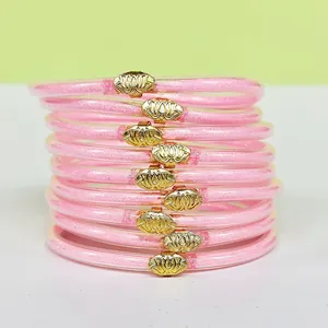 Détail de 9 bracelets en silicone à paillettes roses avec breloques lotus or
