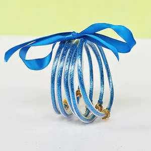 Close-up of blue glitter-filled silicone bangles tied with a blue satin ribbon bow.