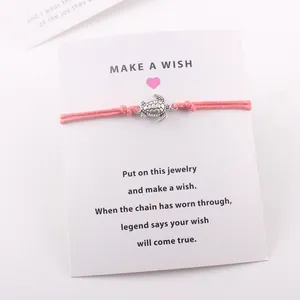 Vue détaillée du bracelet tortue rose monté sur une carte de vœux Make a Wish personnalisée