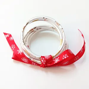 Detalle de pulseras navideñas de silicona con estampado de renos y cinta roja de nieve.
