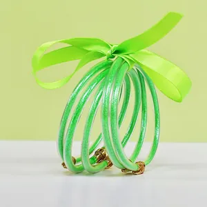 Set of 5 neon green silicone glitter bangles tied with a matching elegant ribbon bow