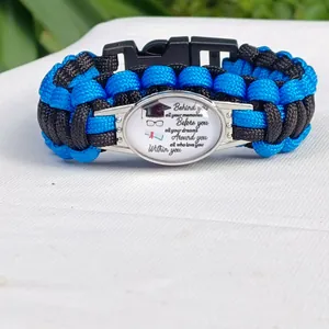 Dettaglio di bracciale in paracord blu e nero con elemento centrale a tema laurea