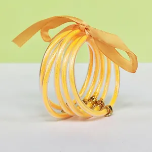 Detailed view of 5-layer gold glitter silicone bangles with an orange ribbon bow