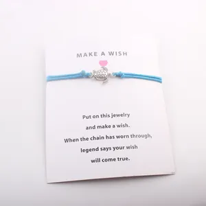 Détail du bracelet en cordon bleu avec breloque tortue sur une carte de vœux Make a Wish