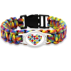Handmade rainbow paracord bracelet featuring a colorful puzzle heart charm and black buckle