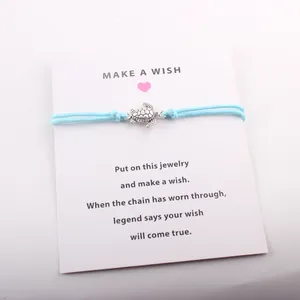 Détail d'un bracelet de vœux tortue avec cordon bleu clair sur une carte de cadeau