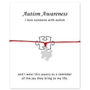 Detail van zilveren puzzelstukje bedel aan rood waskoord armband voor autisme bewust.