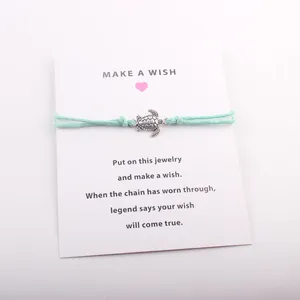 Détail du bracelet de vœux tortue avec cordon turquoise sur carte cadeau porte-bonheur