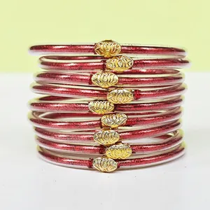 Gros plan de 9 bracelets en silicone rouge pailleté avec d'élégants fermoirs en lotus doré