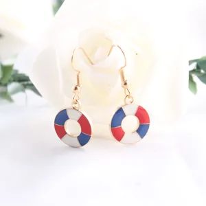 Detail shot of nautical lifebuoy earrings with red, white, and blue enamel patterns.