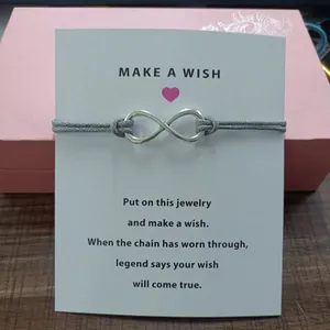 Detailed macro view of a silver infinity charm cord bracelet on a white Make a Wish card