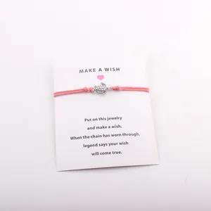 Vue détaillée d'un bracelet de vœux tortue rose sur une carte de présentation Make a Wish
