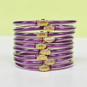 Gros plan de 9 bracelets en silicone à paillettes violettes avec boucles de lotus dorées