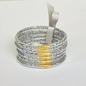 Detailed view of six silver glitter silicone bangles featuring gold wire wrap and a ribbon