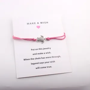 Détail de la breloque tortue en argent sur un bracelet à vœux rose avec carte