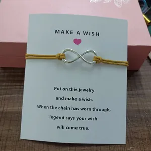Detailed view of infinity symbol wish bracelet with yellow cord on card.