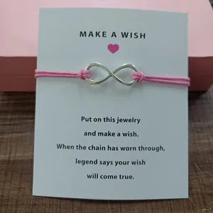 Close-up detail of a silver infinity symbol on a pink string wish bracelet card