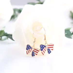Detailed close-up of enamel American flag bow dangle earrings on a white rose background