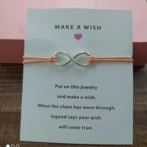 Detailed view of infinity charm bracelet on Make a Wish card with peach cord string