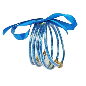 Stylish set of 5 blue glitter silicone bangles featuring a ribbon bow and gold lotus charms