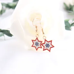 Close-up of USA flag-inspired star dangle earrings with red white and blue enamel