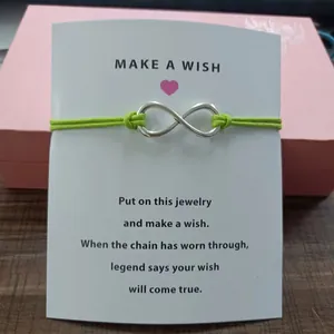 Green string infinity symbol charm bracelet on a white Make A Wish blessing card