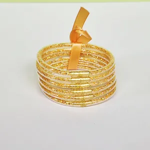 Macro detailed view of six-layer gold glitter silicone bangles with orange ribbon tie