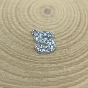 Macro view of 15mm rhinestone letter S pendant for DIY jewelry on wooden base