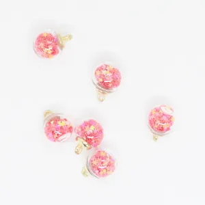Macro detail of 16mm round glass ball pendants filled with pink star-shaped sequins.