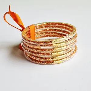 Close-up of orange glitter silicone bangles with gold-tone accents.