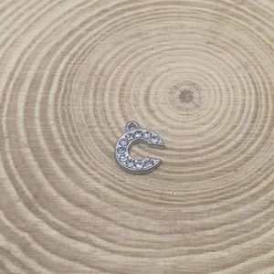 Macro view of a 15mm silver rhinestone-inlaid letter C pendant for DIY jewelry making.