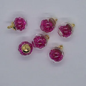 Detail of 16mm clear glass ball charms filled with vibrant pink rhinestones for DIY jewelry.