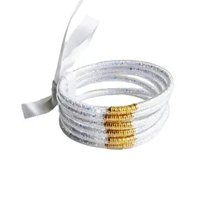 Set of 5 glitter filled silicone bangles with gold connectors and white ribbon bow.