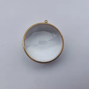 Primer plano de un colgante de caja Gawu de cristal convexo con marco de acero inoxidable dorado