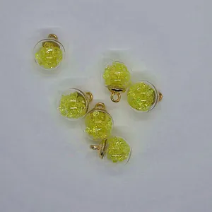 Detail of 16mm round glass ball pendant filled with yellow sparkling stones for DIY jewelry