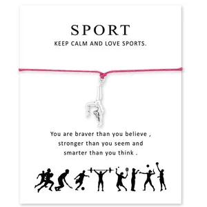 Gros plan d'un bracelet de gymnaste en argent sur un cordon rose avec carte de sport.