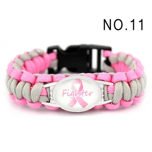 Dettaglio di un braccialetto in paracord intrecciato rosa e grigio con ciondolo Fighter rosa