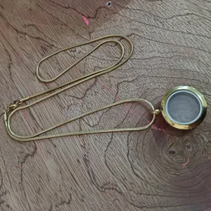 Vue détaillée d'un médaillon flottant en verre et acier doré avec chaîne serpent