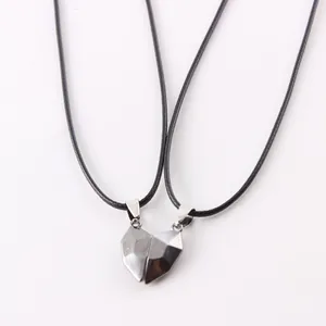 Close-up of faceted magnetic heart-shaped pendants on black cord necklaces for couples