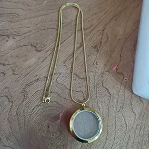 Vue détaillée du collier médaillon flottant rond en verre et acier inoxydable doré.