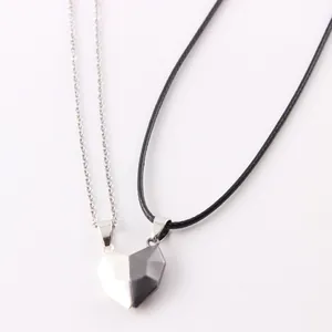 Close-up detail of magnetic heart shaped couple necklaces with black and white pendants