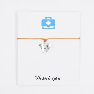 Detailed view of orange wax rope bracelet with winged tooth charm on Thank You card