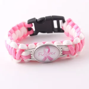 Dettaglio del bracciale in paracord rosa e bianco con ciondolo Fighter nastro cancro al seno